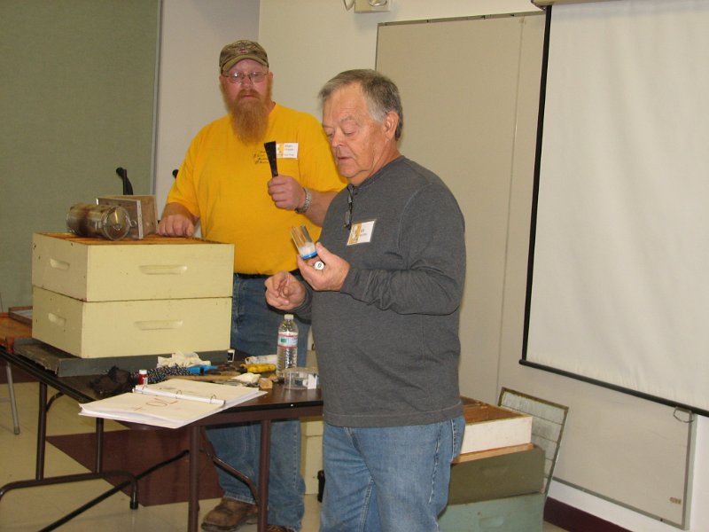 beecourse_day1 025.JPG - Allen holds a hive tool as Bill demonsrates how to mark a queen bee.